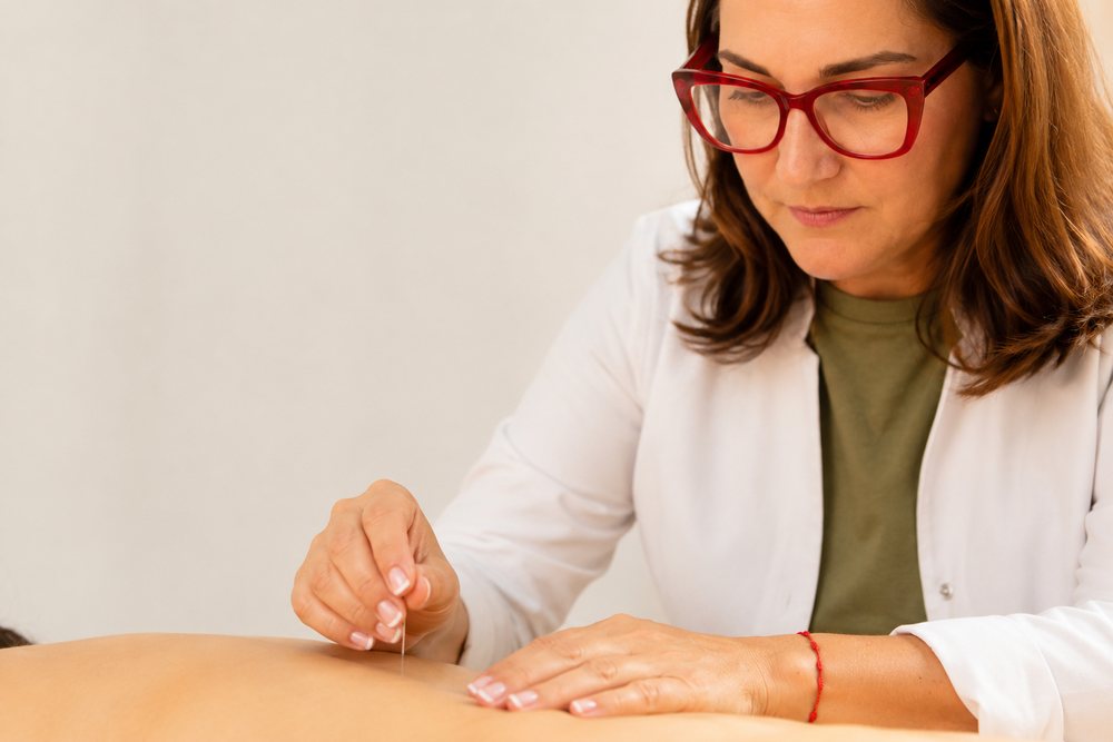 Detalle de las manos de María Piedad Hernández Bilbao insertando una aguja de acupuntura